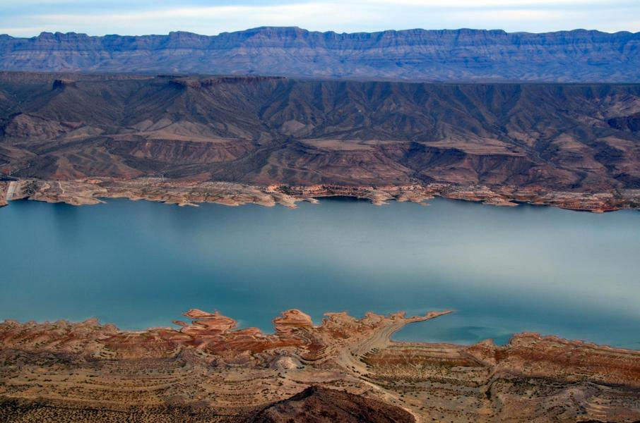 Layers of colorful rock contrast against the deep blue waters