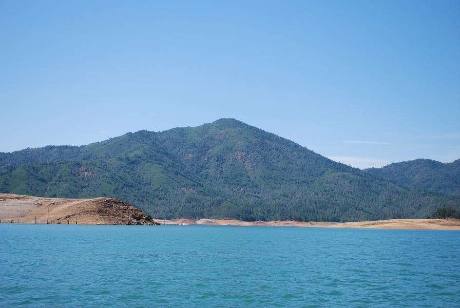 A stunning view of vast blue waters sit below lush green mountains