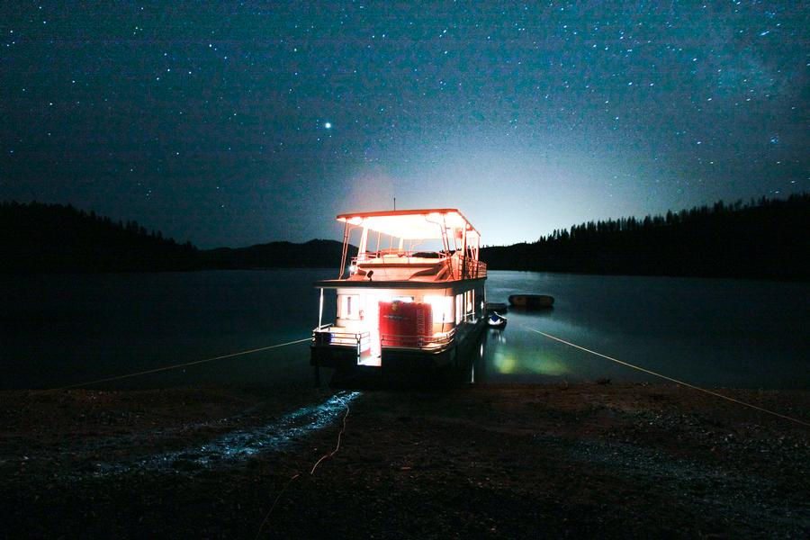 Shining lights from your houseboat illuminate against the star filled sky